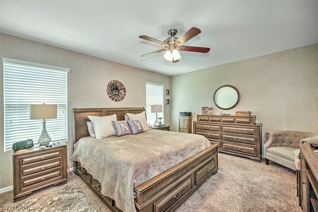 bedroom with multiple windows, ceiling fan, and light carpet