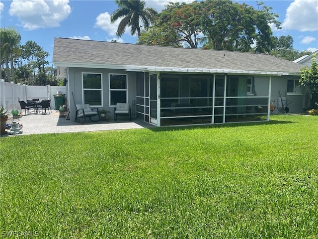 rear view of property with a sunroom, a patio area, and a lawn