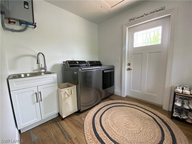 clothes washing area with cabinets, dark hardwood / wood-style flooring, washing machine and clothes dryer, and sink