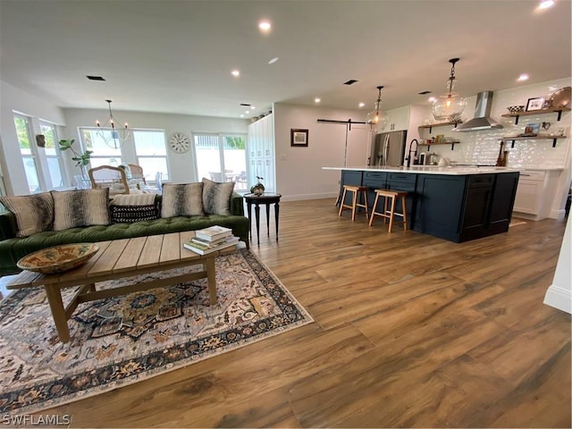 living room with a barn door, wood-type flooring, sink, and an inviting chandelier