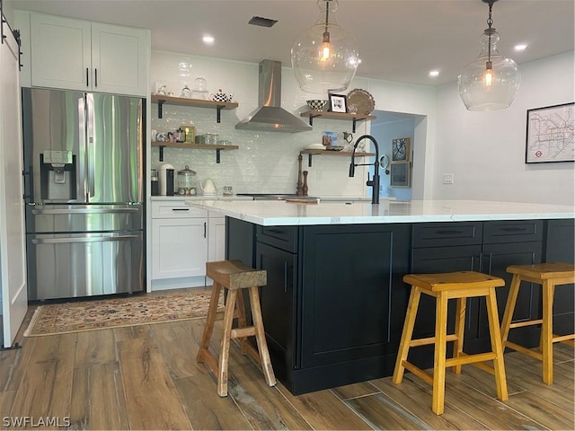 bar with tasteful backsplash, a barn door, island exhaust hood, white cabinets, and appliances with stainless steel finishes