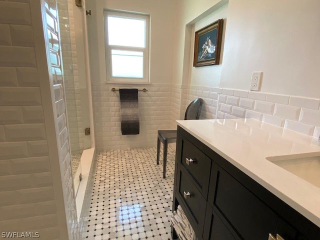 bathroom featuring a shower, sink, tile walls, and tile patterned flooring