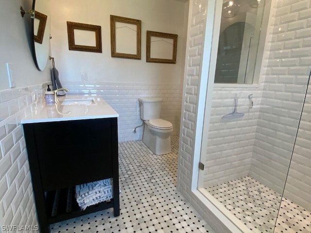 bathroom with vanity, tile patterned flooring, toilet, tile walls, and a shower with shower door