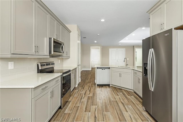 kitchen featuring light wood-type flooring, stainless steel appliances, gray cabinets, and sink