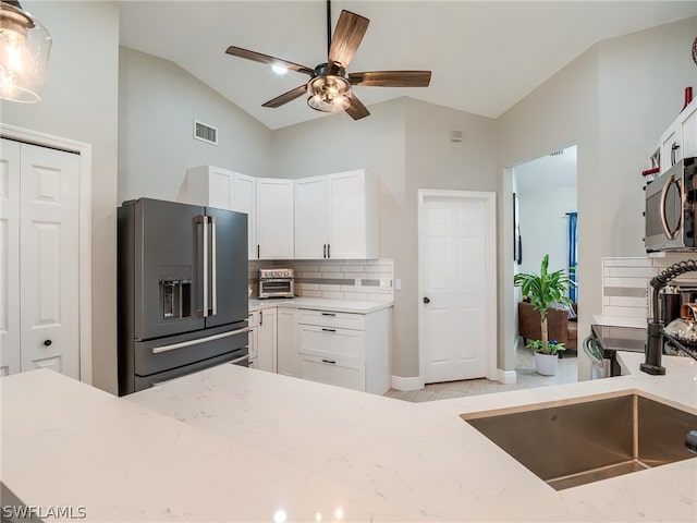 kitchen featuring stainless steel appliances, sink, ceiling fan, light stone counters, and white cabinets