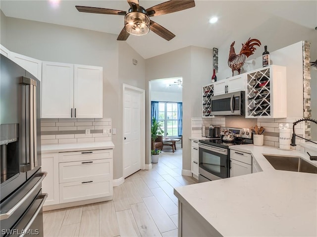 kitchen with white cabinetry, appliances with stainless steel finishes, sink, and lofted ceiling