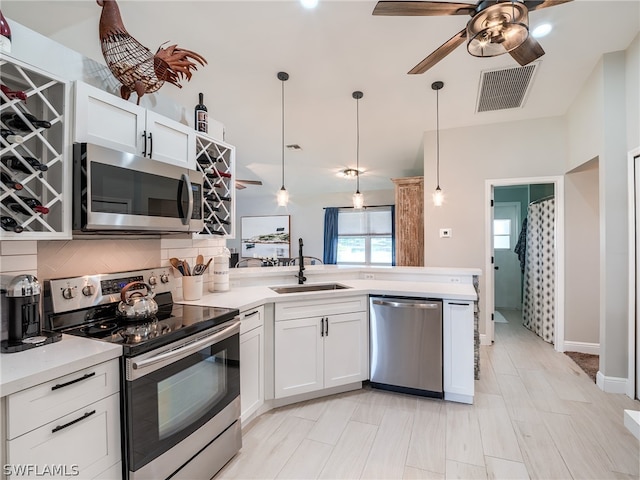 kitchen with white cabinetry, stainless steel appliances, sink, ceiling fan, and decorative backsplash