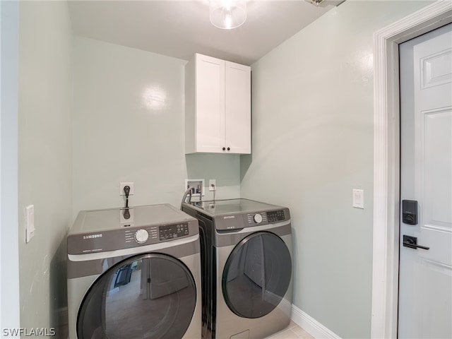 clothes washing area with cabinets and washer and clothes dryer