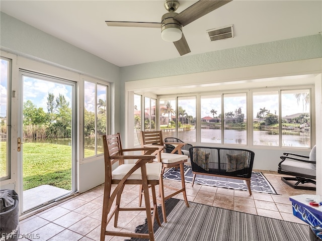 sunroom / solarium featuring a water view, ceiling fan, and a healthy amount of sunlight