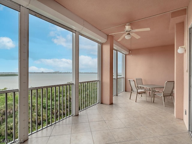 sunroom featuring ceiling fan and a water view