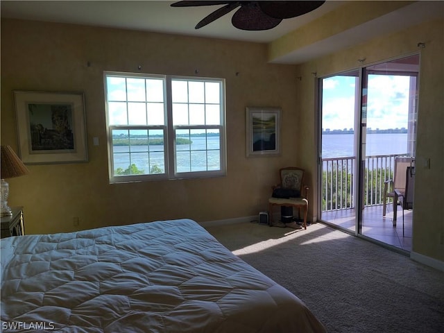 carpeted bedroom featuring access to outside, ceiling fan, and a water view