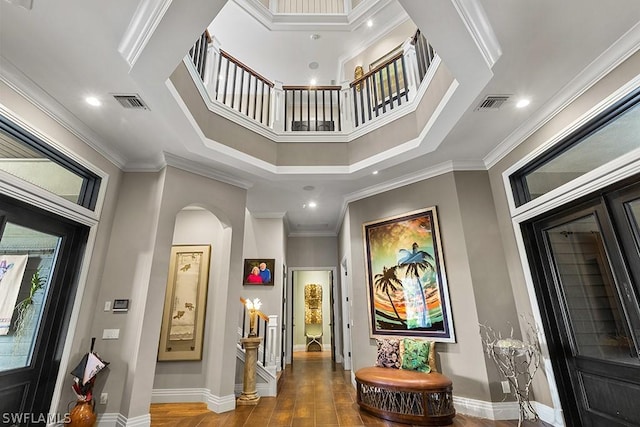 hall with crown molding, wood-type flooring, and a high ceiling