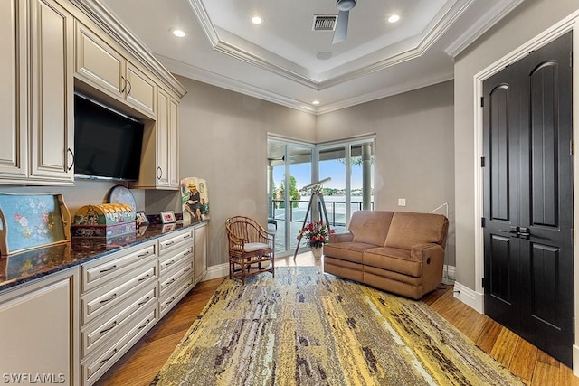 sitting room with light hardwood / wood-style floors, ornamental molding, and a tray ceiling