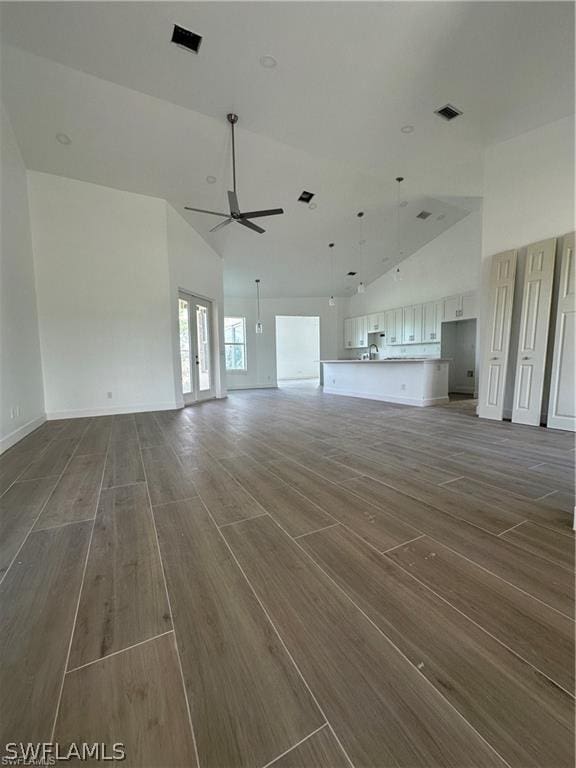 unfurnished living room with ceiling fan and vaulted ceiling