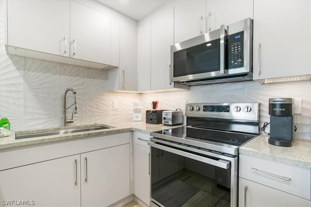 kitchen with stainless steel appliances, sink, decorative backsplash, and white cabinets