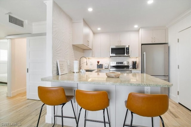 kitchen featuring white cabinetry, stainless steel appliances, kitchen peninsula, and sink