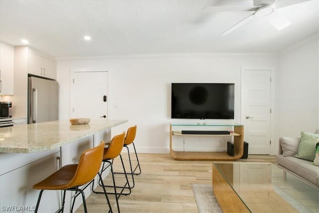 kitchen featuring light hardwood / wood-style flooring, stainless steel fridge, a kitchen breakfast bar, light stone countertops, and white cabinets