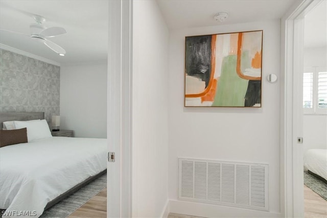 bedroom with crown molding, wood-type flooring, and ceiling fan