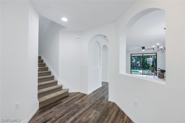 corridor featuring dark wood-type flooring and an inviting chandelier