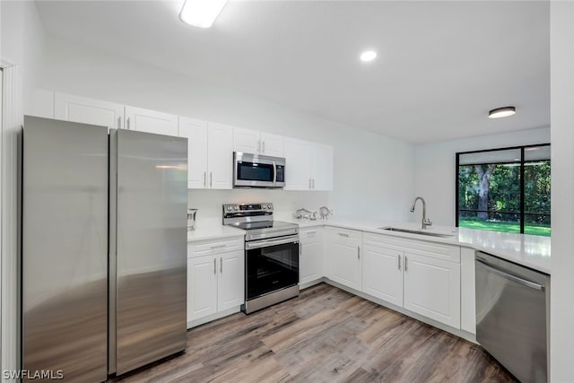 kitchen featuring white cabinetry, sink, light hardwood / wood-style floors, and appliances with stainless steel finishes