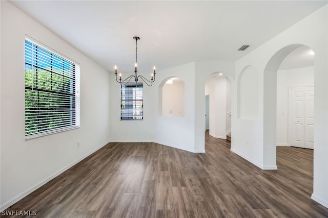 unfurnished dining area with dark hardwood / wood-style flooring and a notable chandelier