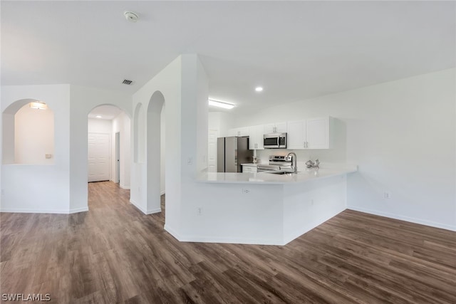 kitchen featuring white cabinets, appliances with stainless steel finishes, dark hardwood / wood-style floors, and kitchen peninsula