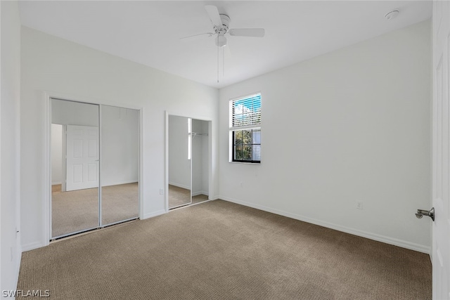 unfurnished bedroom featuring ceiling fan, light carpet, and two closets