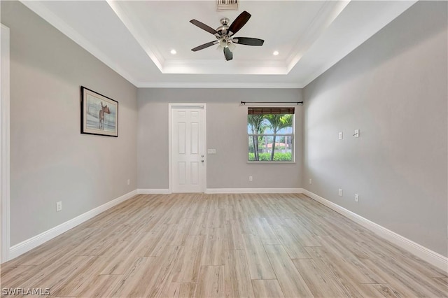 unfurnished room with ceiling fan, light hardwood / wood-style floors, and a tray ceiling