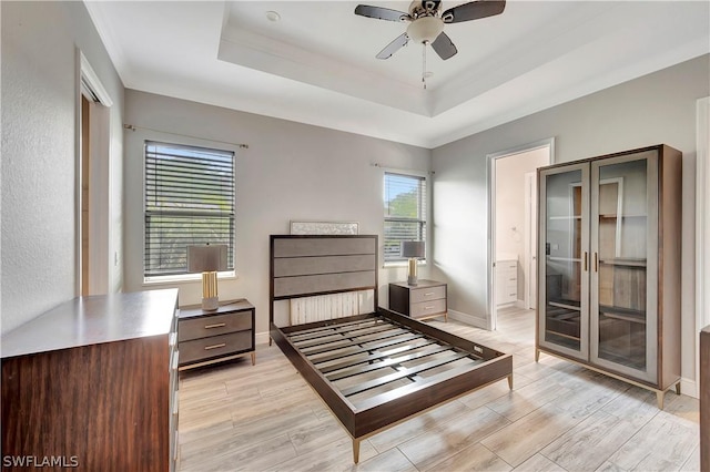 bedroom featuring ceiling fan, connected bathroom, and a tray ceiling