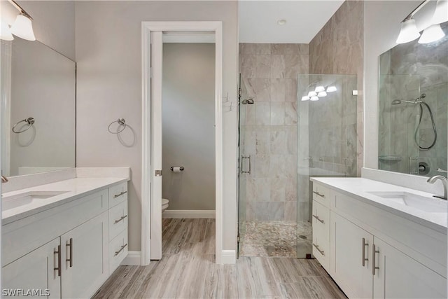 bathroom featuring vanity, hardwood / wood-style flooring, a shower with door, and toilet