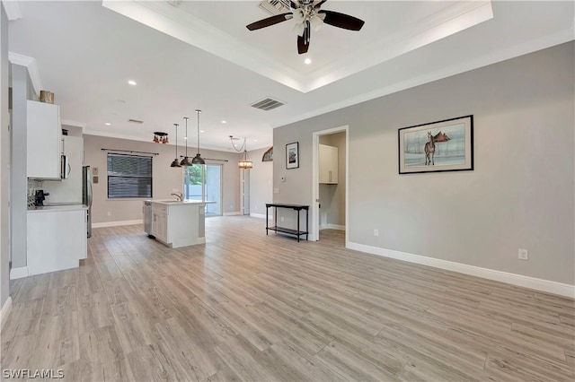 unfurnished living room featuring a raised ceiling, ceiling fan, sink, and light wood-type flooring