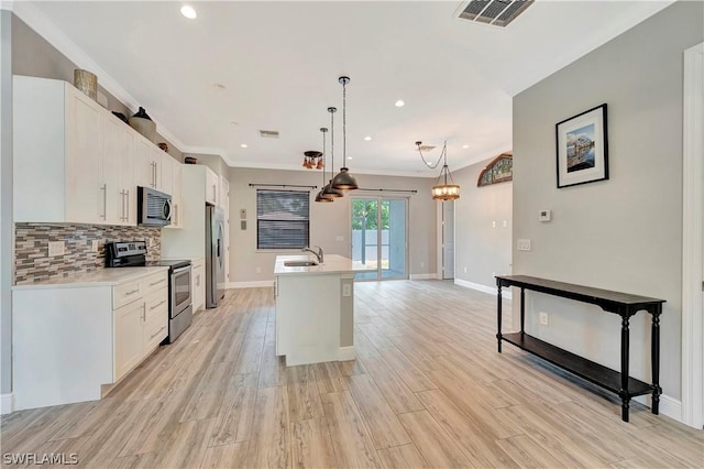 kitchen with appliances with stainless steel finishes, decorative light fixtures, an island with sink, sink, and white cabinets