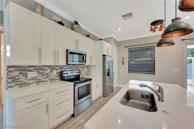 kitchen featuring decorative light fixtures, white cabinets, and appliances with stainless steel finishes