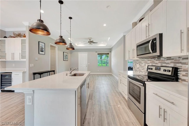 kitchen featuring sink, stainless steel appliances, beverage cooler, a kitchen island with sink, and white cabinets