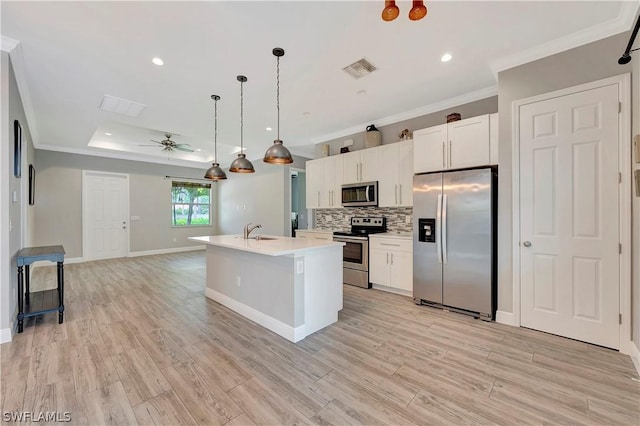 kitchen featuring sink, appliances with stainless steel finishes, white cabinetry, a center island with sink, and decorative light fixtures