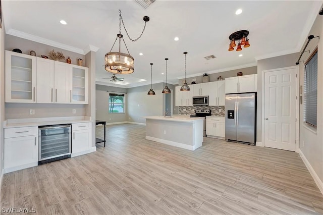 kitchen with pendant lighting, white cabinetry, stainless steel appliances, a kitchen island, and beverage cooler