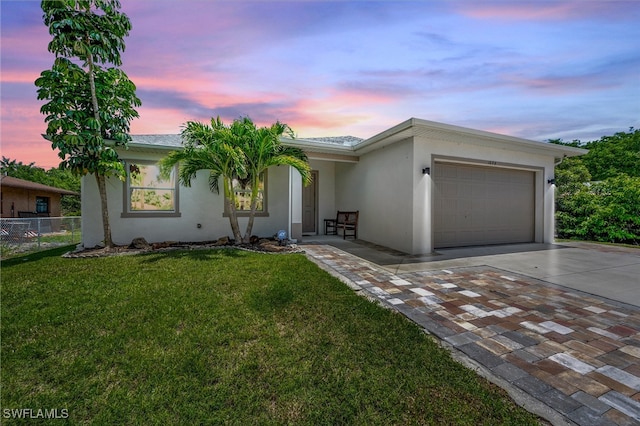 single story home with a garage and a lawn