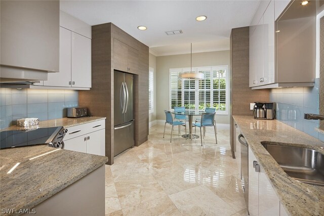 kitchen with pendant lighting, white cabinetry, appliances with stainless steel finishes, and light stone counters