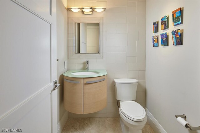 bathroom with vanity, tile walls, and toilet