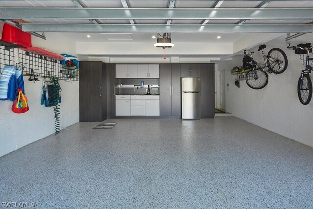 garage with a garage door opener and stainless steel refrigerator