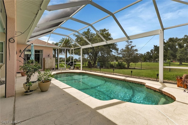 view of pool with a patio, a yard, and glass enclosure