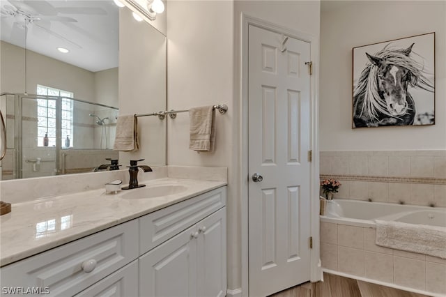 bathroom with hardwood / wood-style flooring, shower with separate bathtub, vanity, and ceiling fan