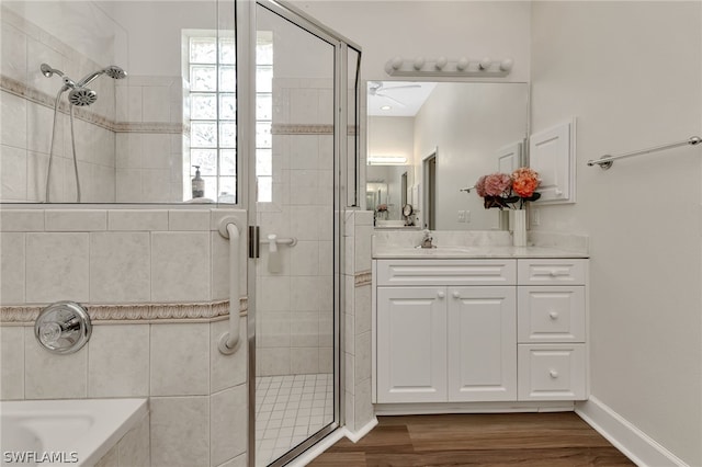 bathroom with hardwood / wood-style flooring, plus walk in shower, vanity, and plenty of natural light