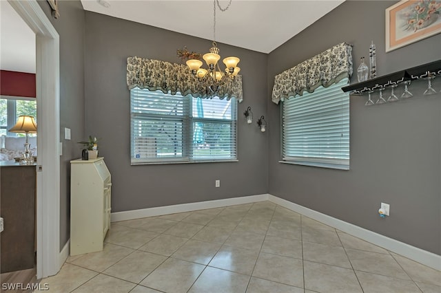 unfurnished dining area with an inviting chandelier and light tile patterned floors