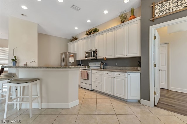 kitchen featuring white cabinets, stainless steel appliances, light hardwood / wood-style floors, and kitchen peninsula