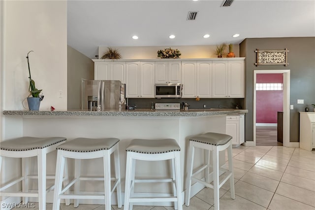 kitchen with a kitchen breakfast bar, light wood-type flooring, stainless steel appliances, and white cabinets