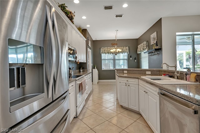 kitchen featuring white cabinetry, light tile patterned floors, light stone counters, appliances with stainless steel finishes, and decorative light fixtures