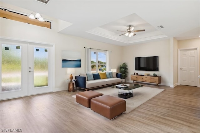 living room featuring ceiling fan, a raised ceiling, french doors, and light hardwood / wood-style flooring