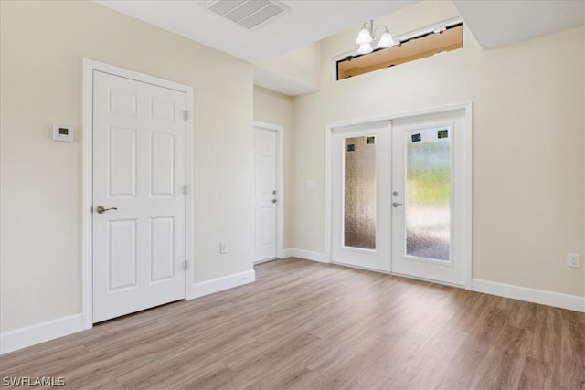 foyer entrance featuring french doors, a chandelier, and light wood-type flooring