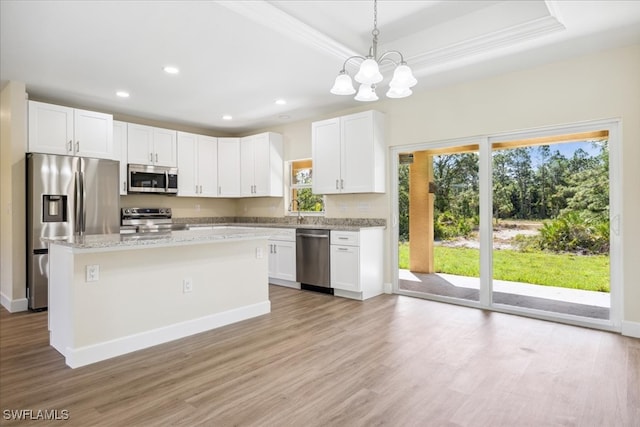 kitchen with a raised ceiling, white cabinetry, a kitchen island, and stainless steel appliances